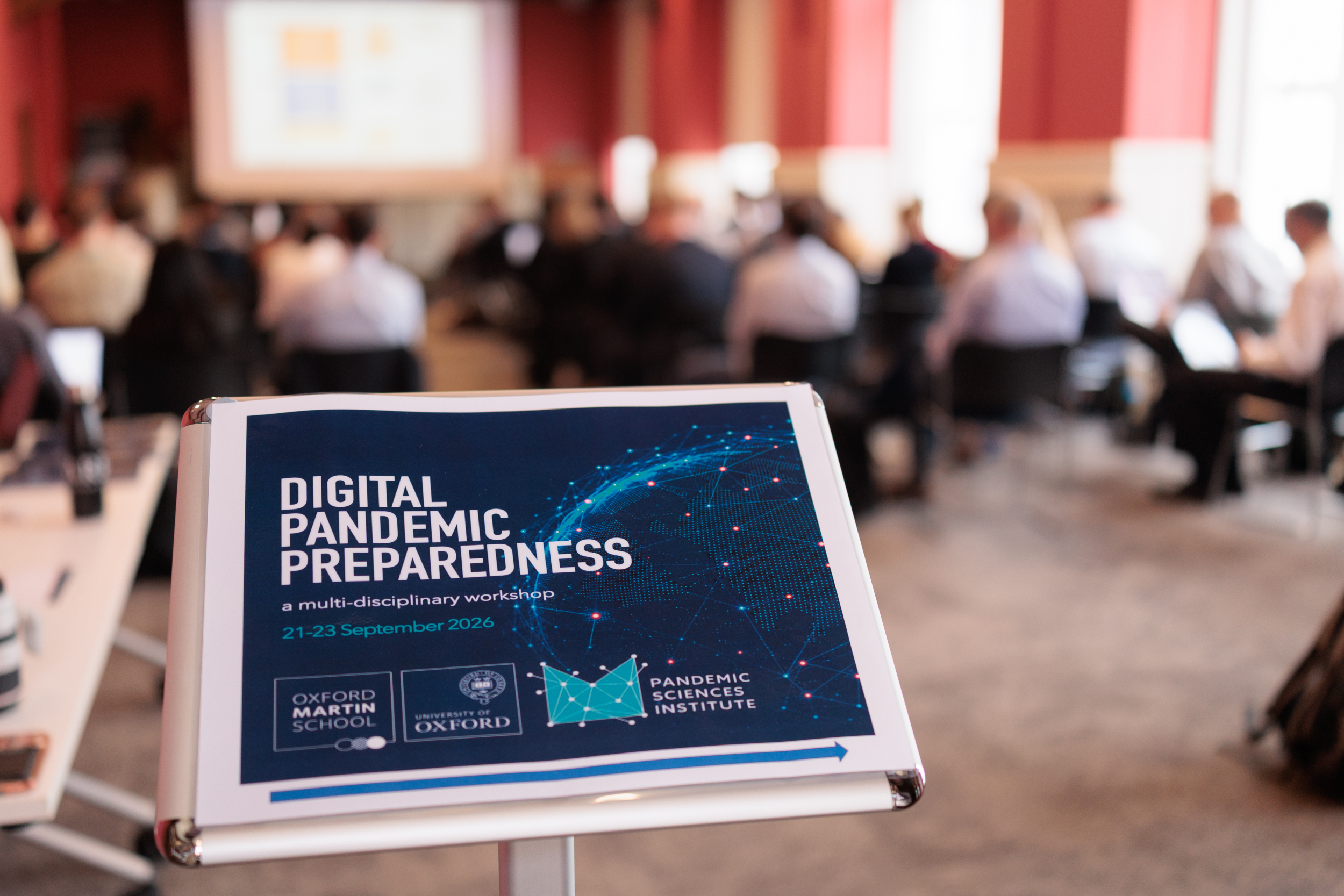 Digital Pandemic Preparedness sign and a blurred room full of delegates.