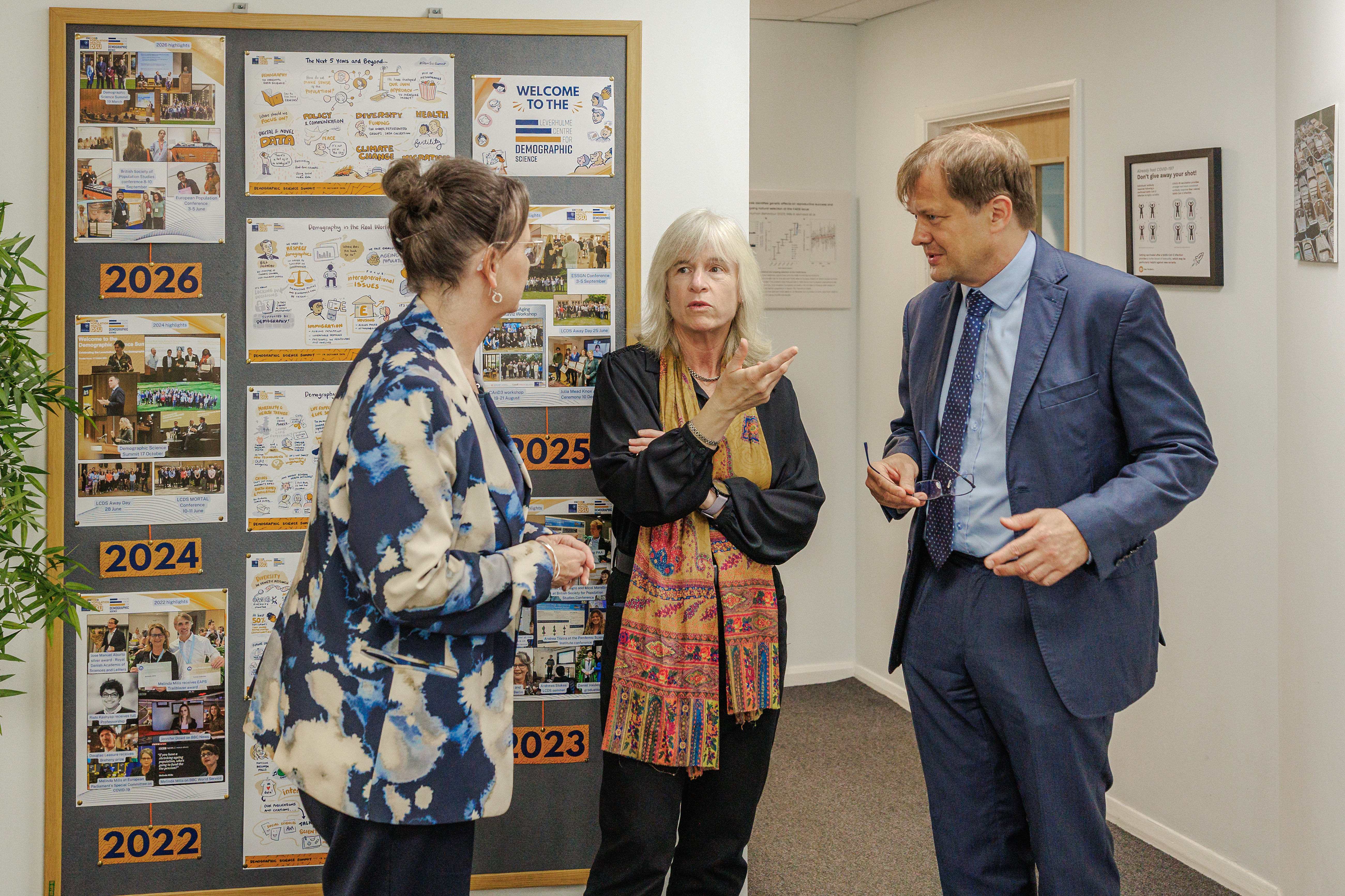 From left to right: Professors Melinda Mills, Anna Vignoles and Jakub Bijak talking in front of the board with LCDS timeline.