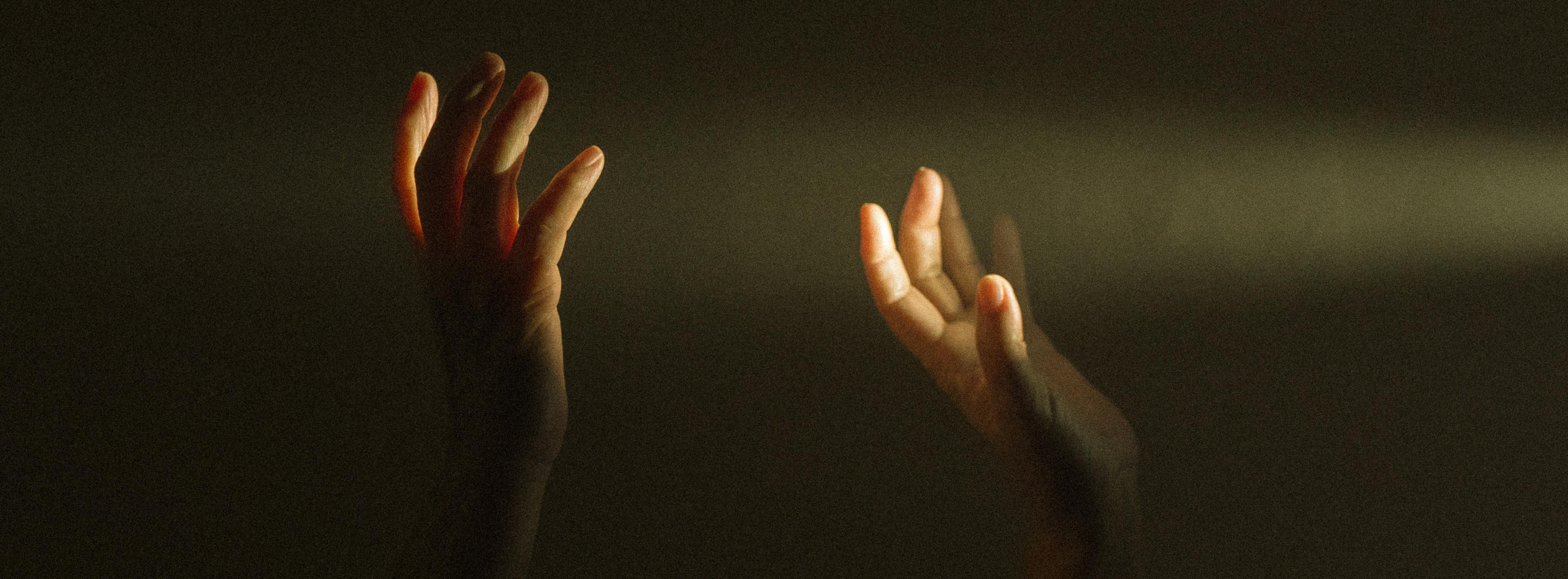 Persons raising hands in darkness