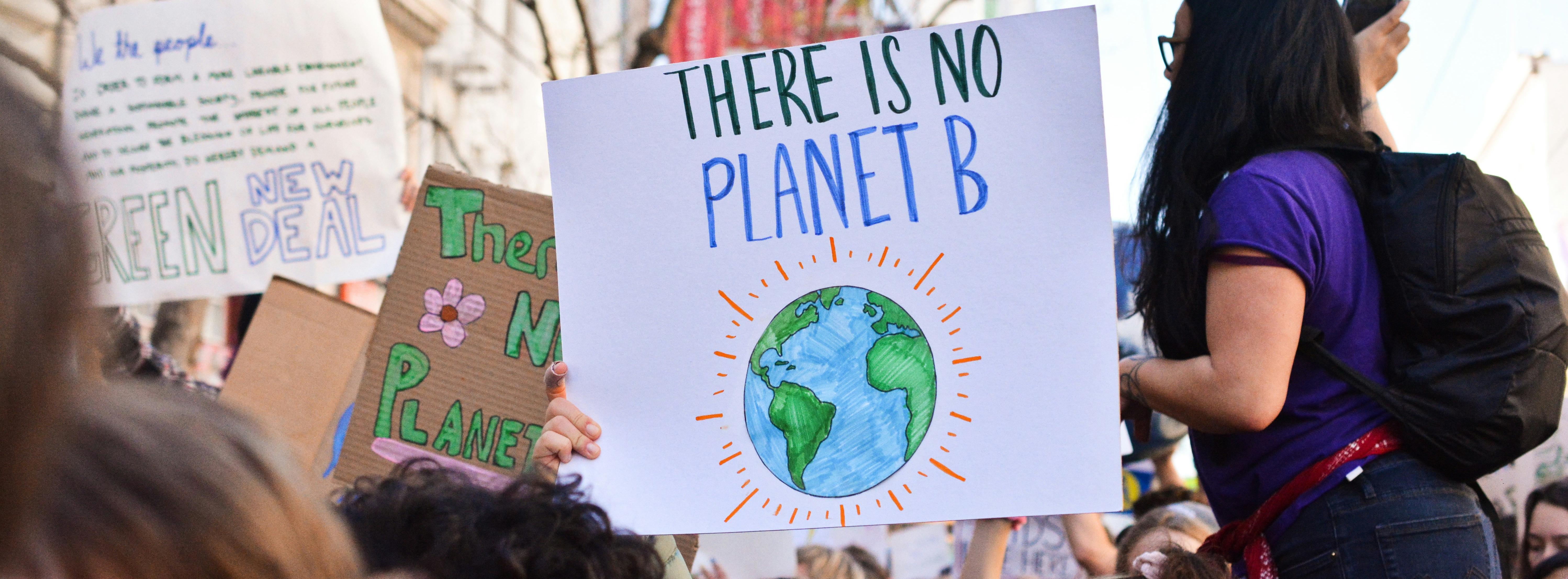 Climate protestors holding signs, including 'There is no planet B' and 'Green New Deal'