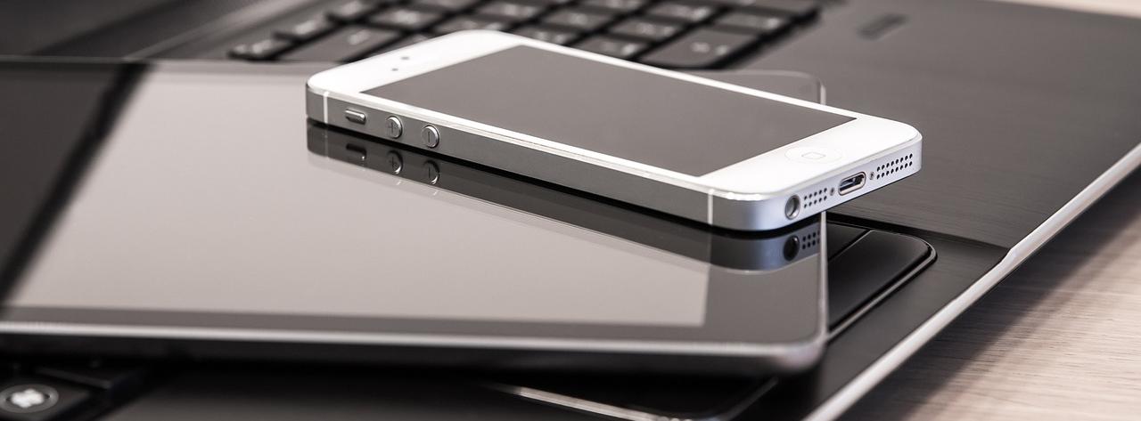 Laptop, iPad and phone stacked on a desk