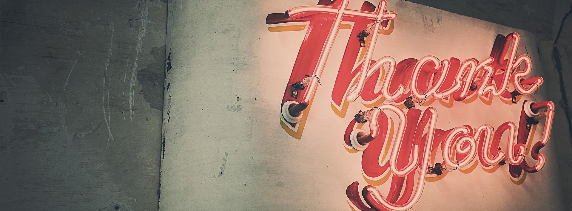 Red neon sign with text 'Thank you' on wall