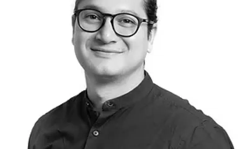 Jose wears glasses and an Oxford shirt that is dark colored. He is smiling at the camera.