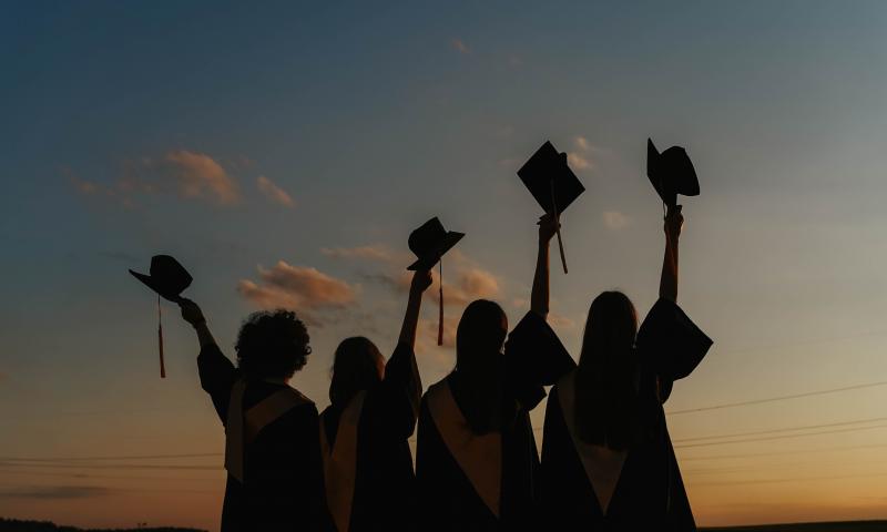 Silhouette of People Raising Their Graduation Hats