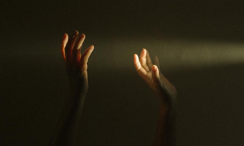Persons raising hands in darkness