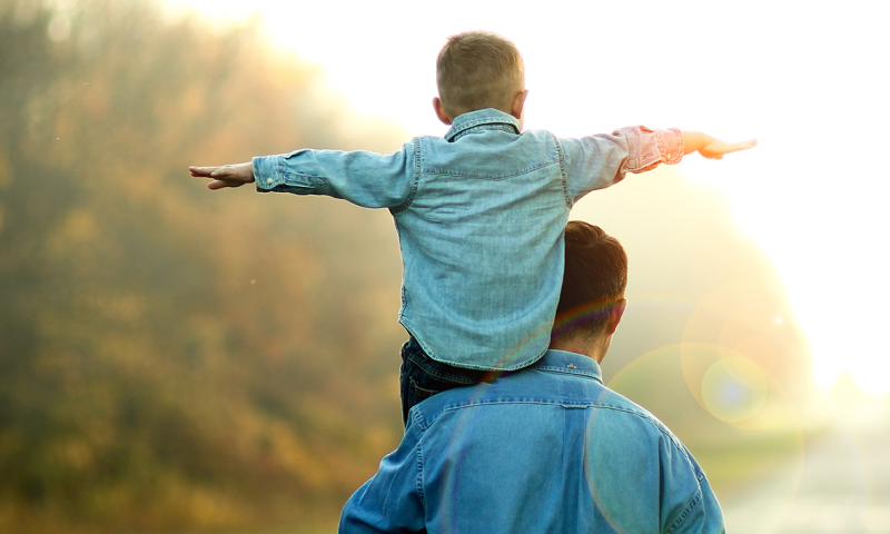 Father giving son a piggyback, surrounded by Nature