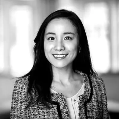 Xuejie wears a tweed suit coat and has dark hair.